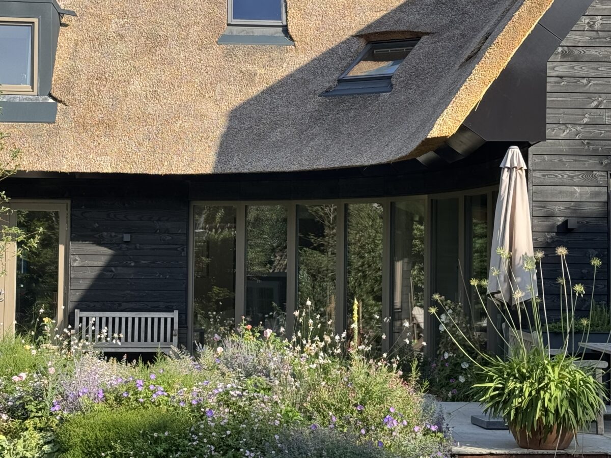 Ronde glazen gevel van de villa in Huizen, gezien vanuit de tuin