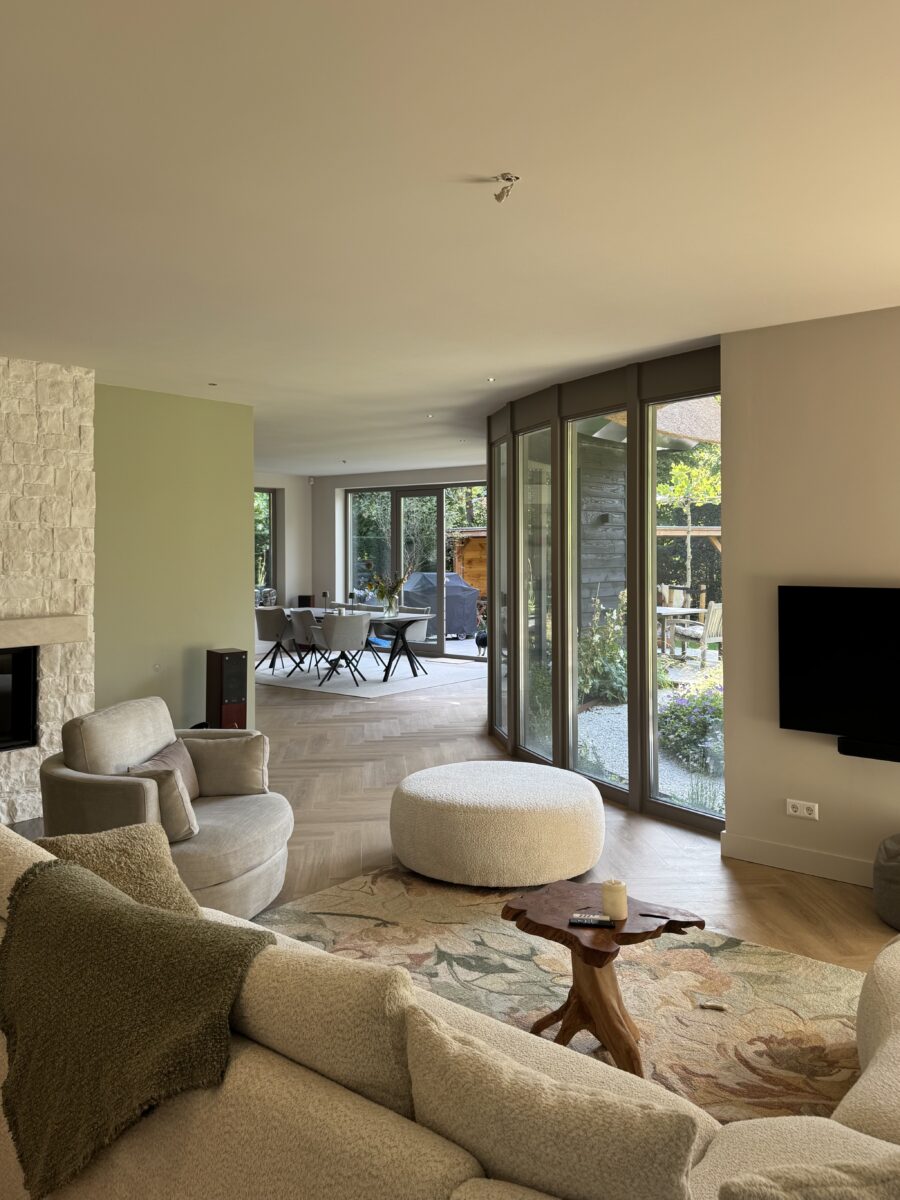 Woonkamer van de villa in Huizen met zicht op de tuin door de ronde glazen gevel